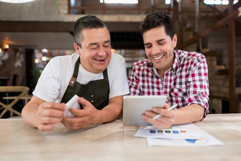 Restaurant worker and consultant discussing report findings on a tablet device