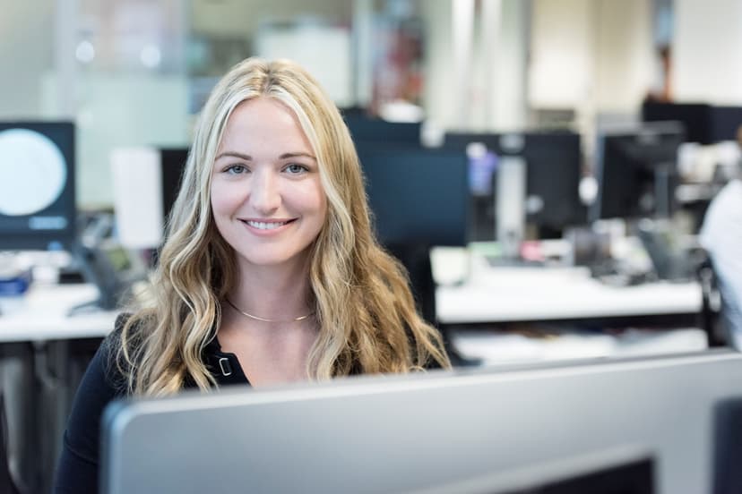 Female sitting at their workstation, smiling at the camera