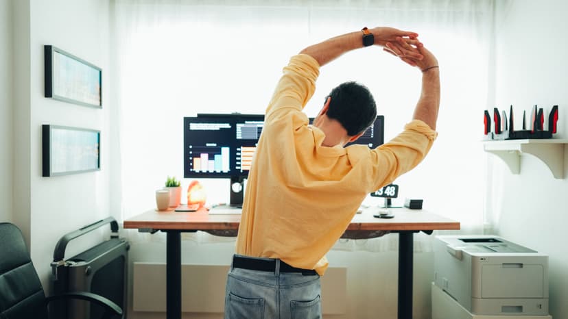Male doing desk stretches at their work from home sit stand desk set up