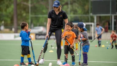 Ellie Cole on the pitch with kids learning to play hockey.