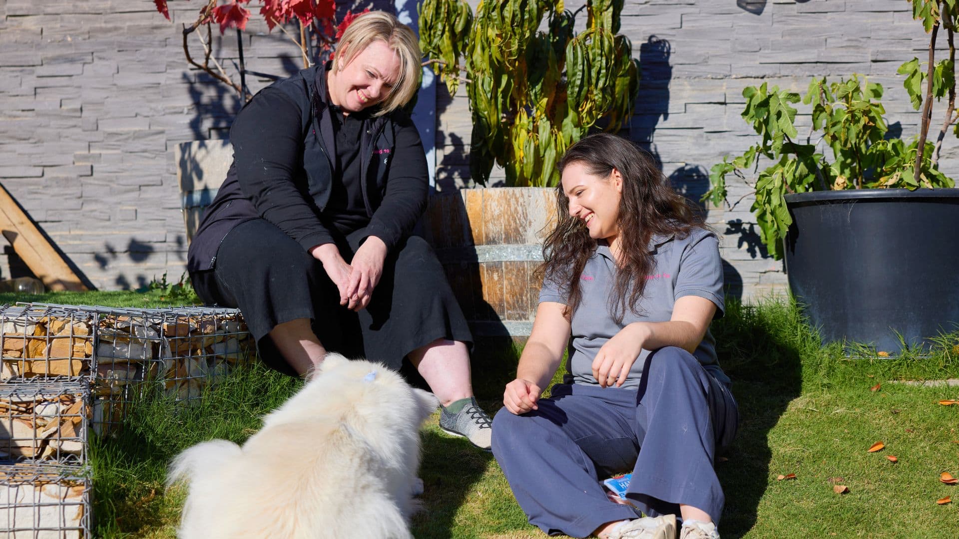 Vicki and her employee Ciana stand outside with a dog