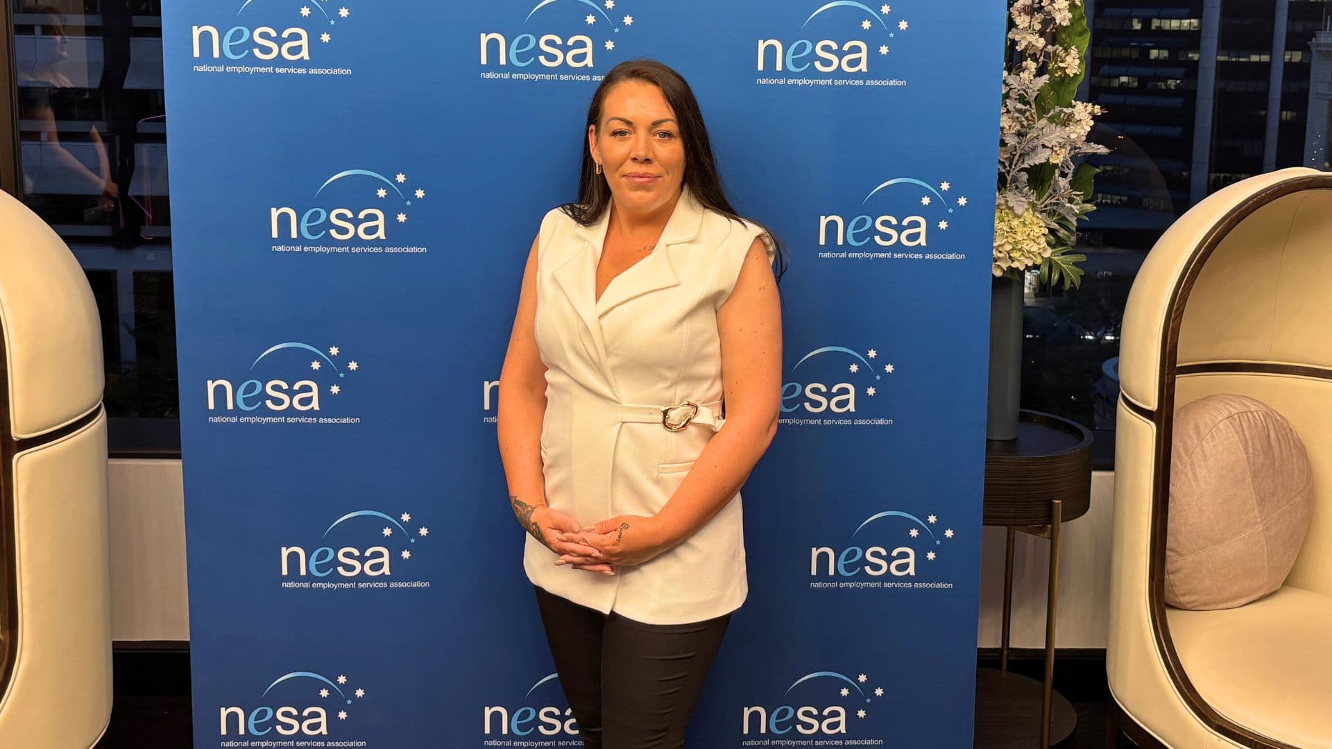 Holly-May stands next to a banner at the NESA awards