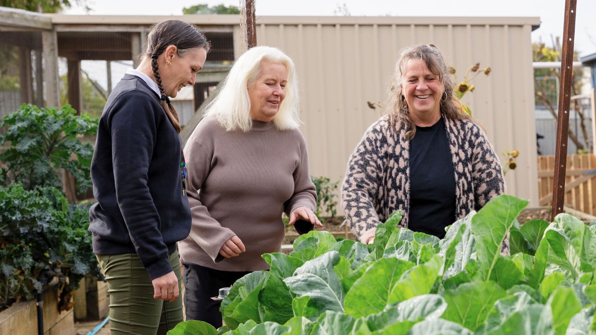 Kylie participates in an indoor activity, holding an insulated bag while another person reaches into a basket, highlighting community support through APM Workforce Australia.