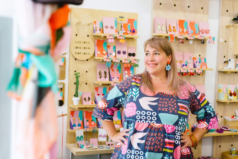 A woman smiles in her own craft and hobby shop