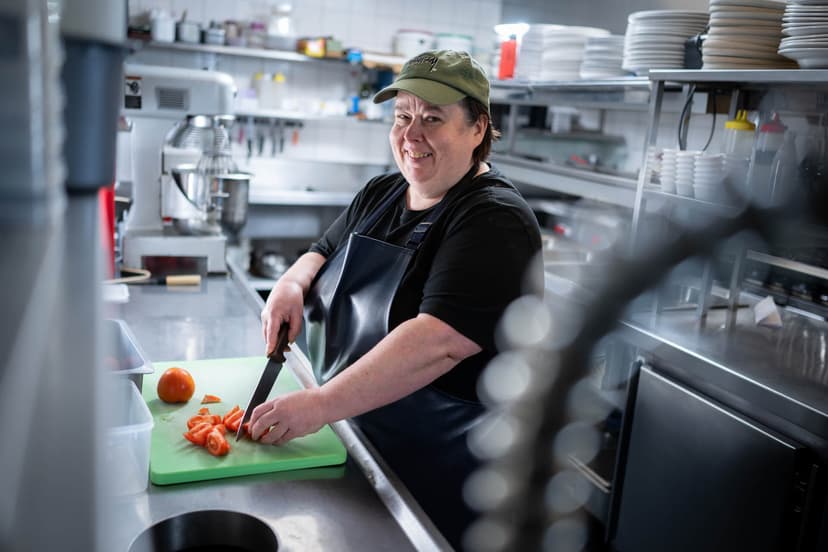 Participant Melissa smiles as she prepares food in the kitchen