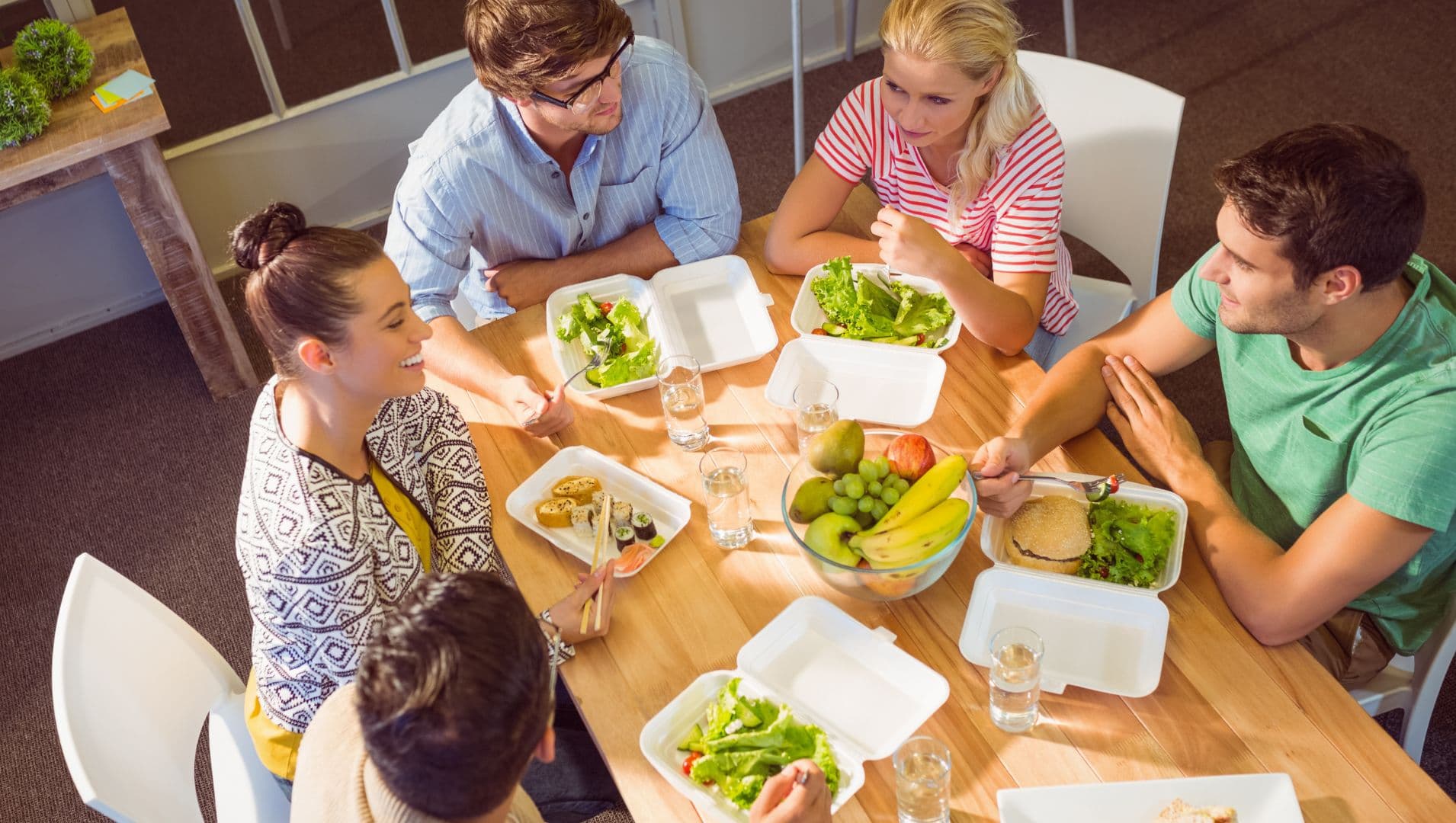 Workers sit round a small table with health food in the middle