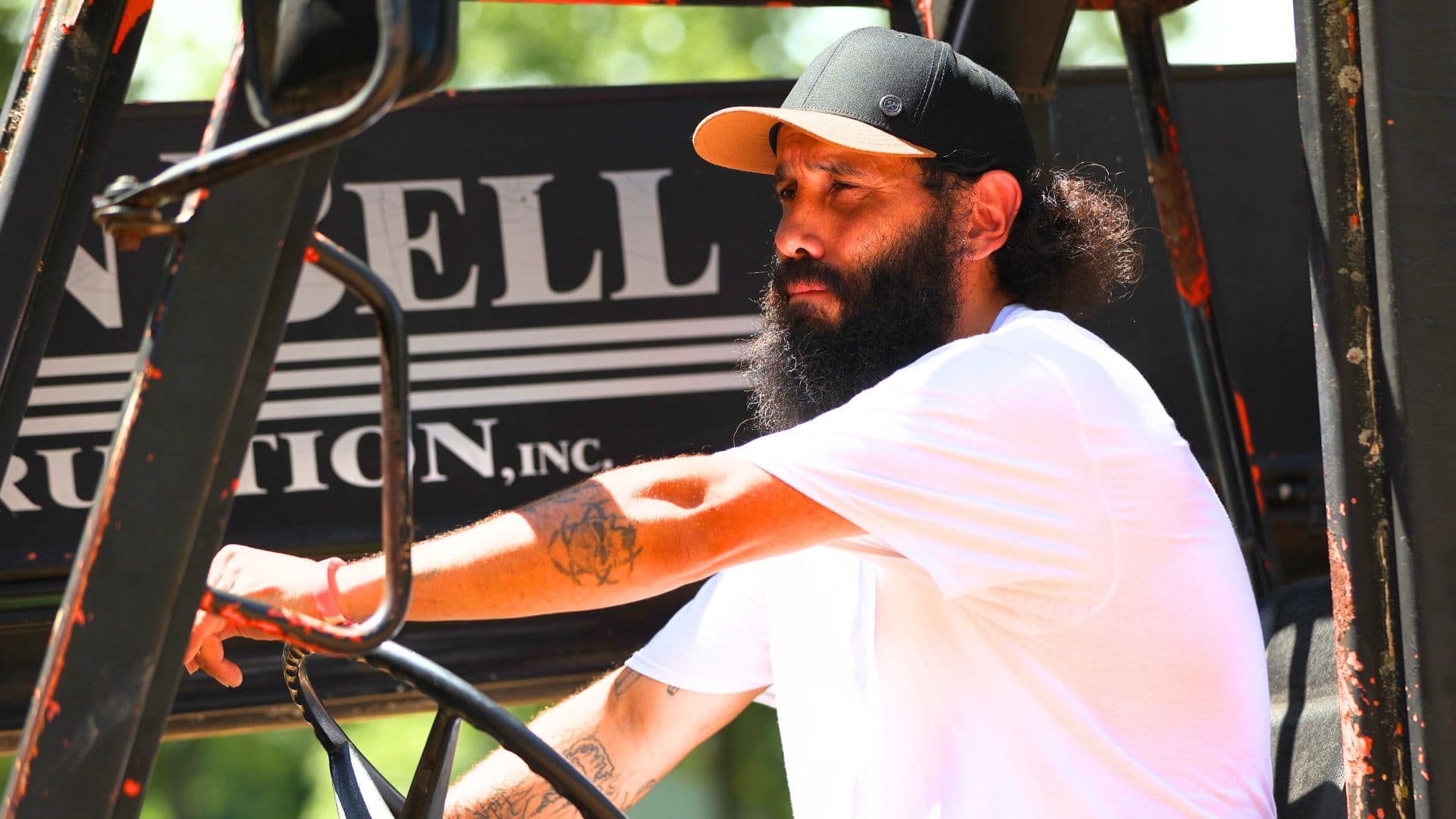 A person with a beard operating heavy machinery.
