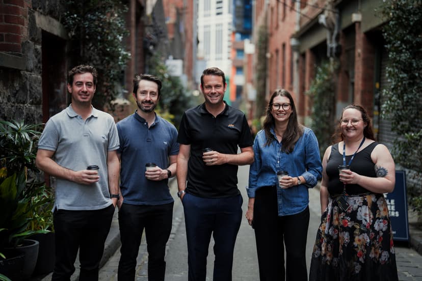Five APM WorkCare team members standing casually in a line holding coffees