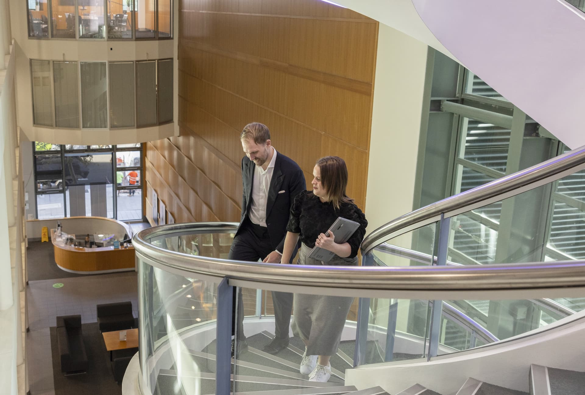 Two office workers walk up a spiral staircase