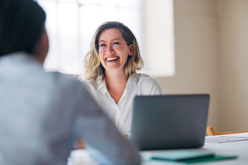 Empowered female worker with glasses engaged in conversation with a laptop in front of her