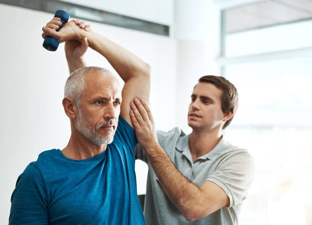 Physio with a patience, doing tricep exercises with a dumbbell weight