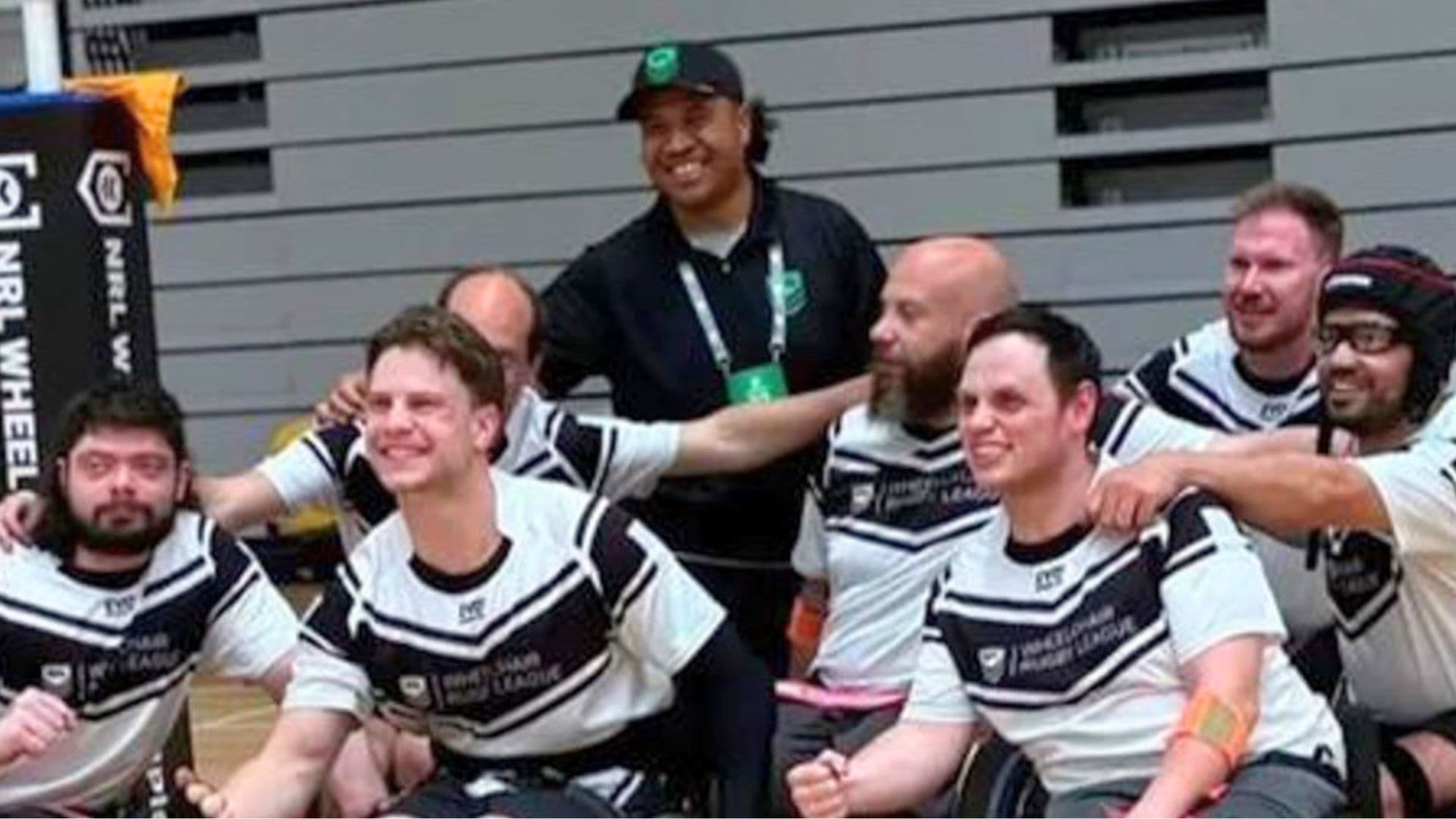 Members of the Victoria Wheelchair Rugby League team pose together in team uniforms at an indoor sports venue ahead of the NRL Wheelchair Championships.