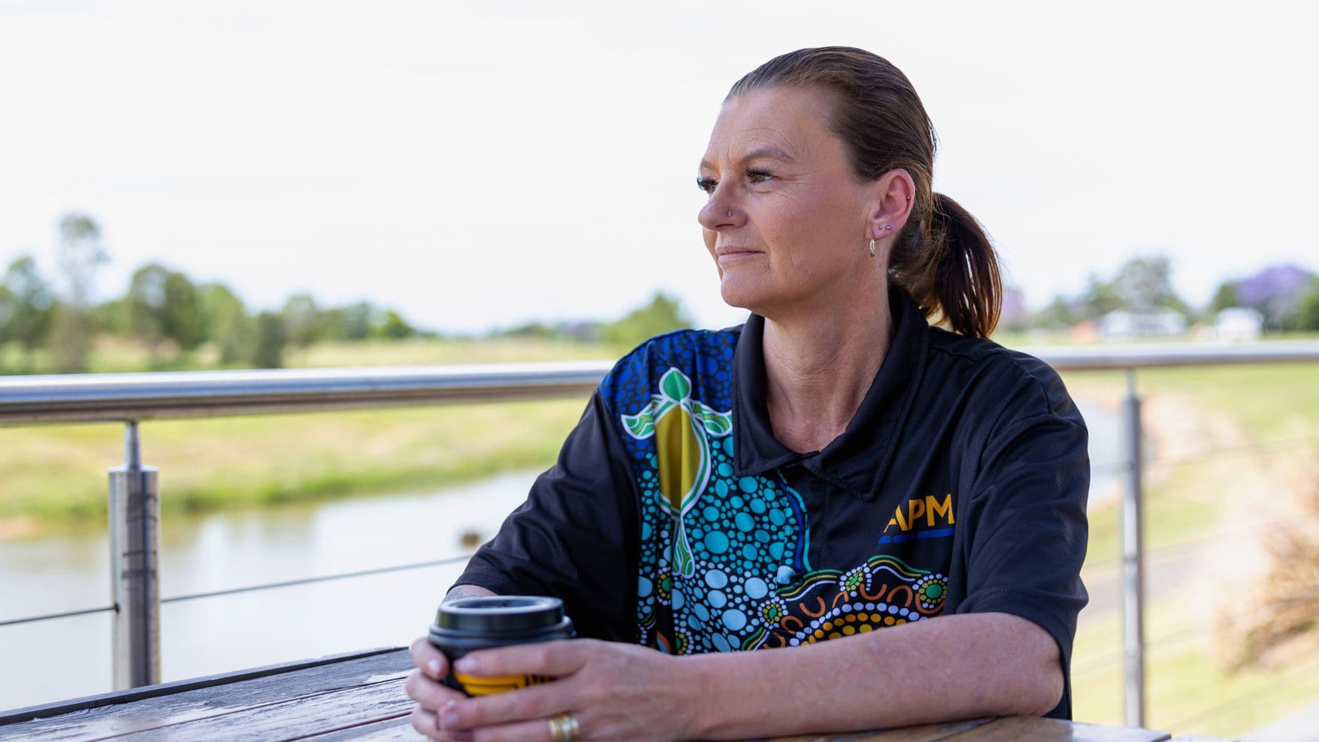 Rochelle from APM's People and Culture team sitting outside with a coffee.