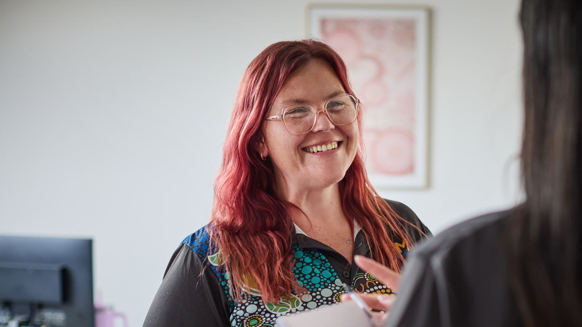 Clare smiles to a participant in APM Collie office
