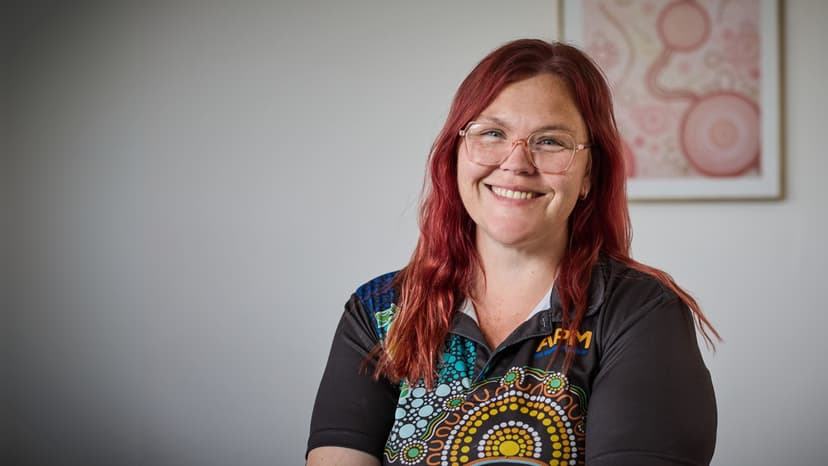 Clare from APM smiling in a First Nations polo