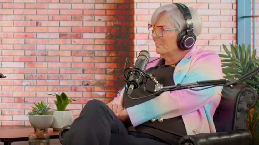 Two people sitting opposite eachother with headphones and podcast recording gear