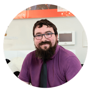 Bearded man with glasses wearing a formal shirt and tie smiles