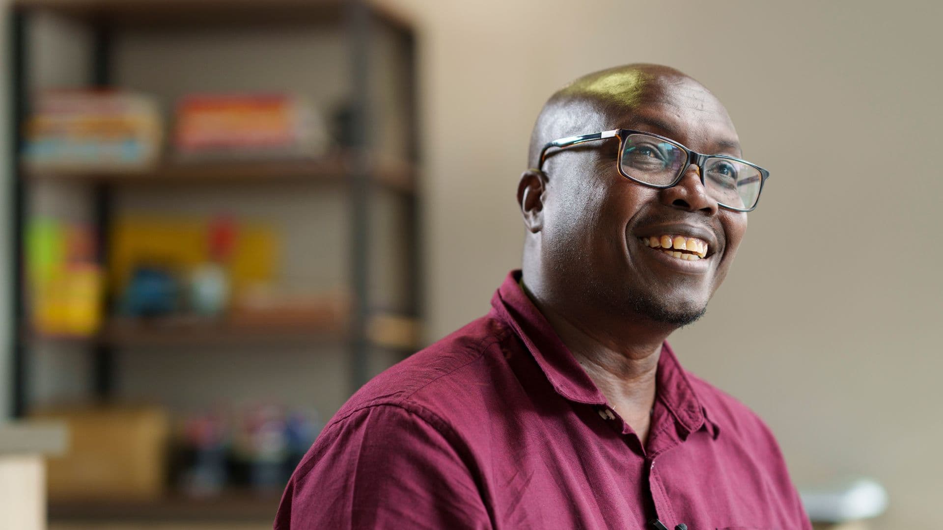 David Mutai smiles on a couch looking into the distance