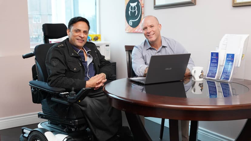 Jasvir smiles in a wheelchair in an office