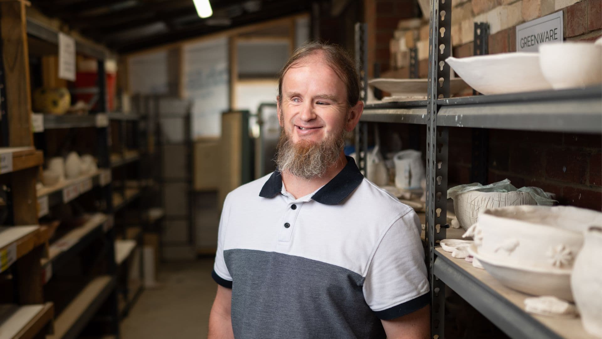 Ben standing next to art shelves in the studio