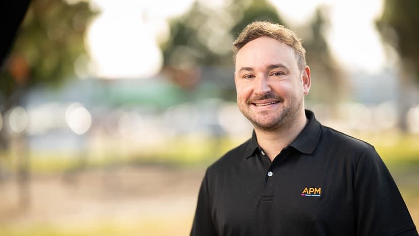 Adam smiles in a black APM polo