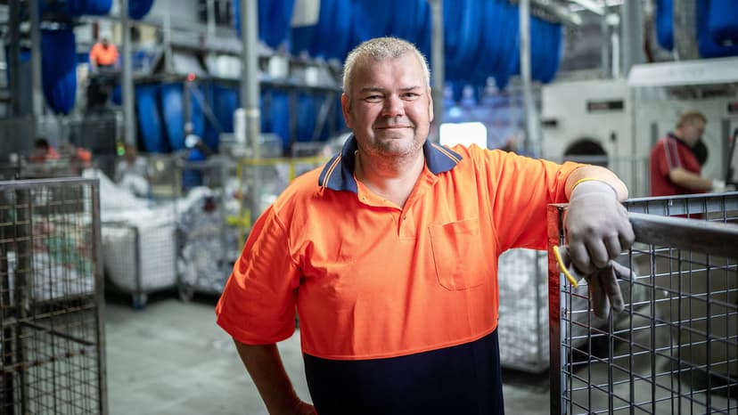 Participant Geoff smiles in an orange top in a warehouse