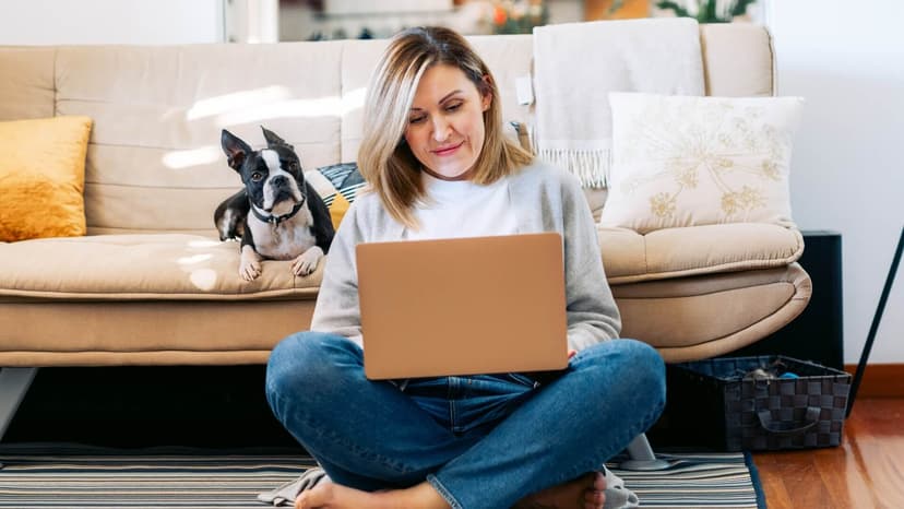 A woman working on her laptop next to her dog