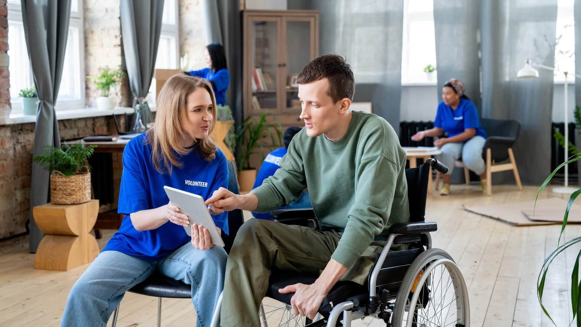 A man in a wheelchair talking to a volunteer