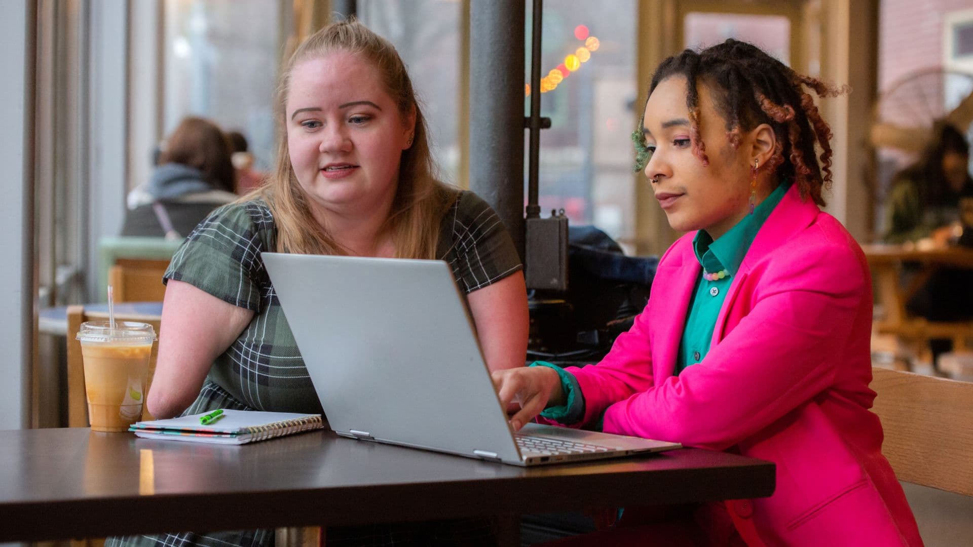 A woman with an amputated arm sits with a woman discussing a support plan