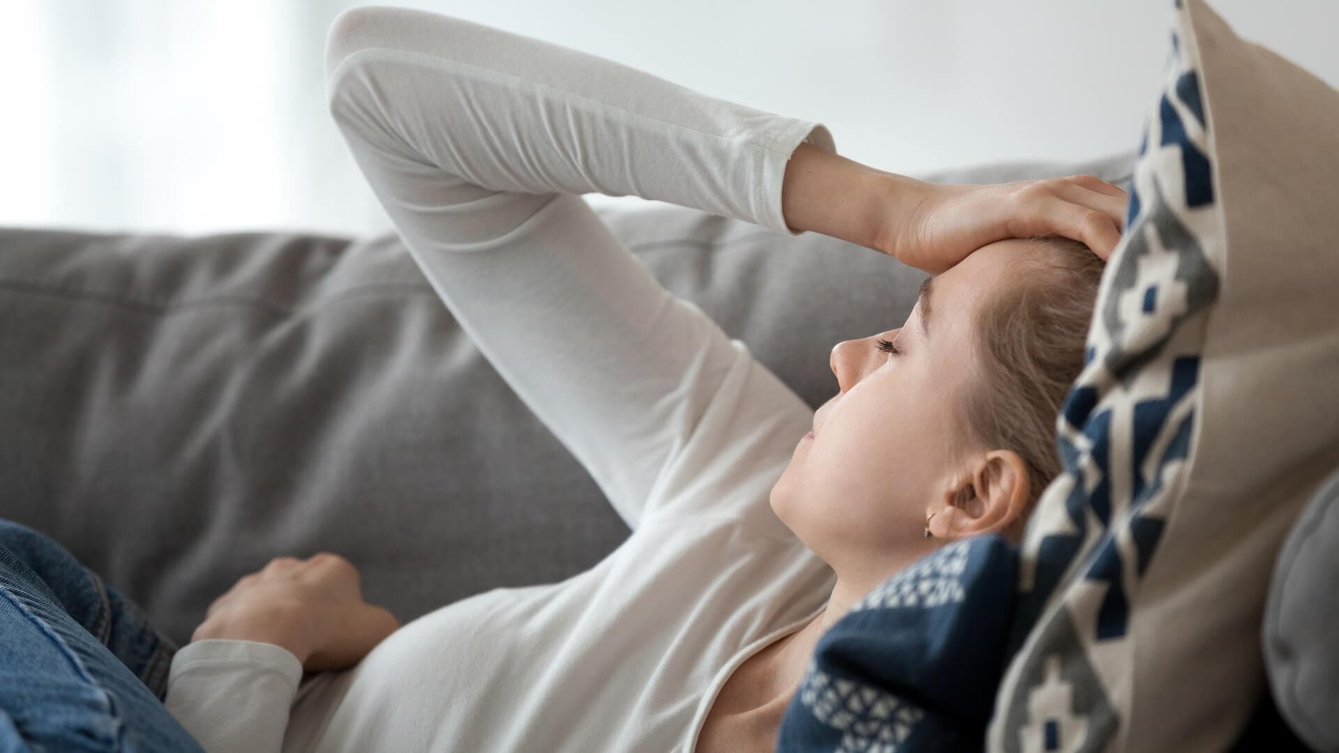 A woman lying on a couch nursing a headache