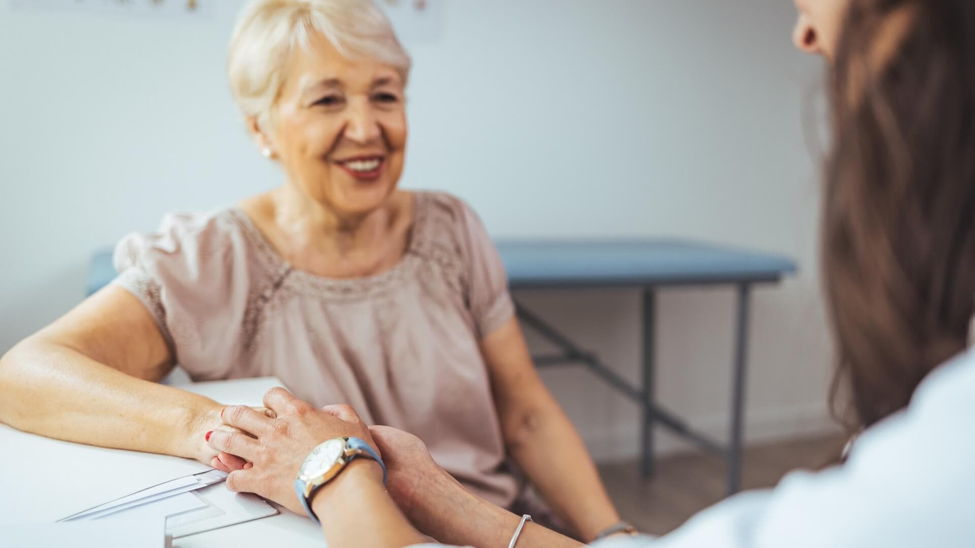 Female nurse holding her senior patient's hand