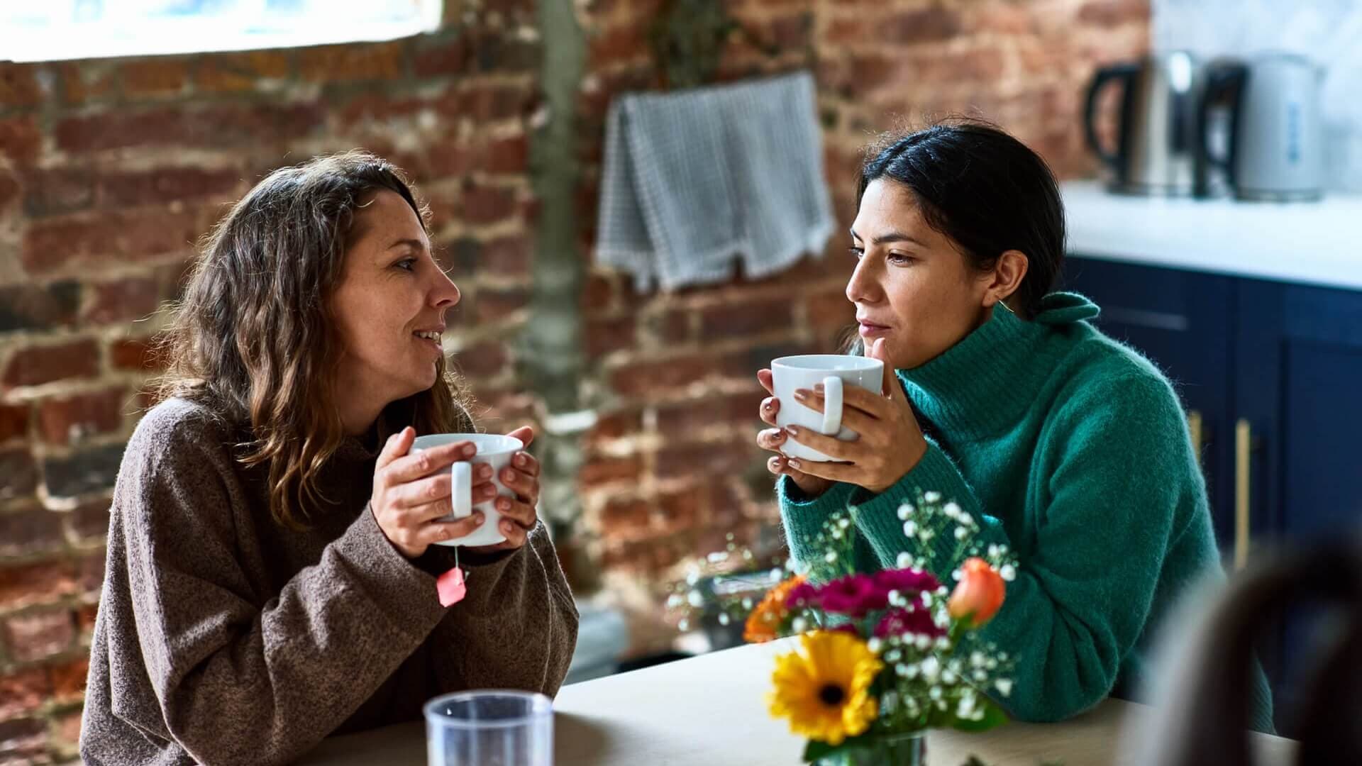Two friends supporting each other through depression with a warm mug of coffee