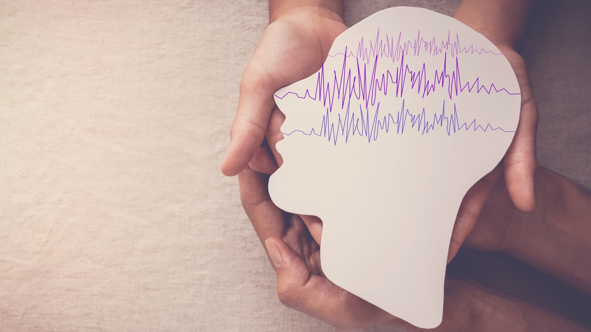 Adult and child hands holding an epilepsy brain paper cut-out