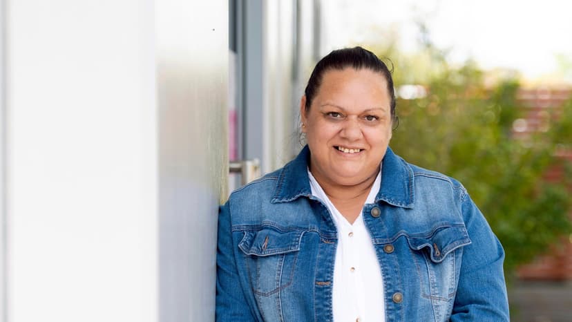 Mel, a First Nations woman, leans on a wall and smiles after support from APM Employment Services
