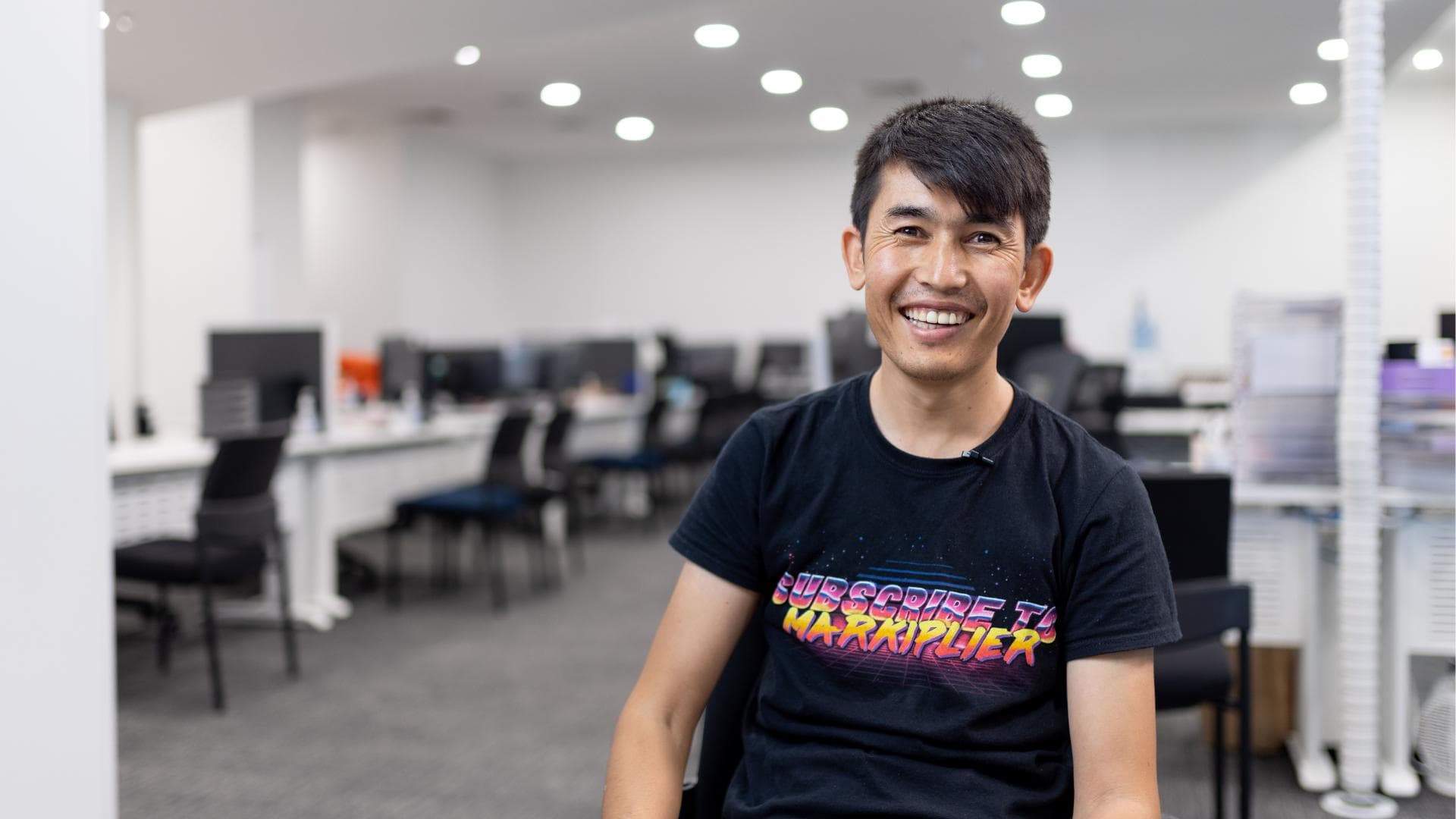 A young man smiles in an APM Employment Services site where he's a participant of Workforce Australia