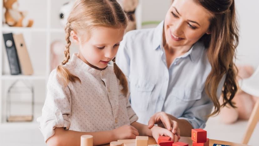 A young girl at a table with a therapist