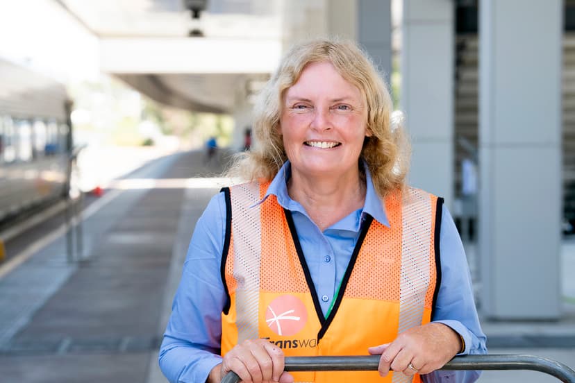 Sharon smiling in high-vis jacket at a train station