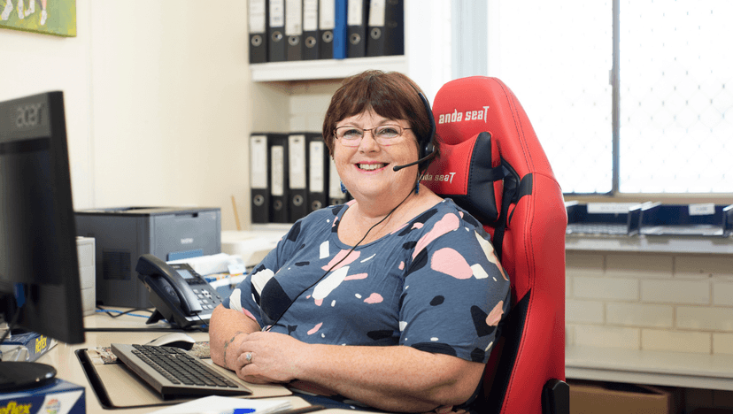 Leonie smiles sitting at her desk in a red ergonomic chair