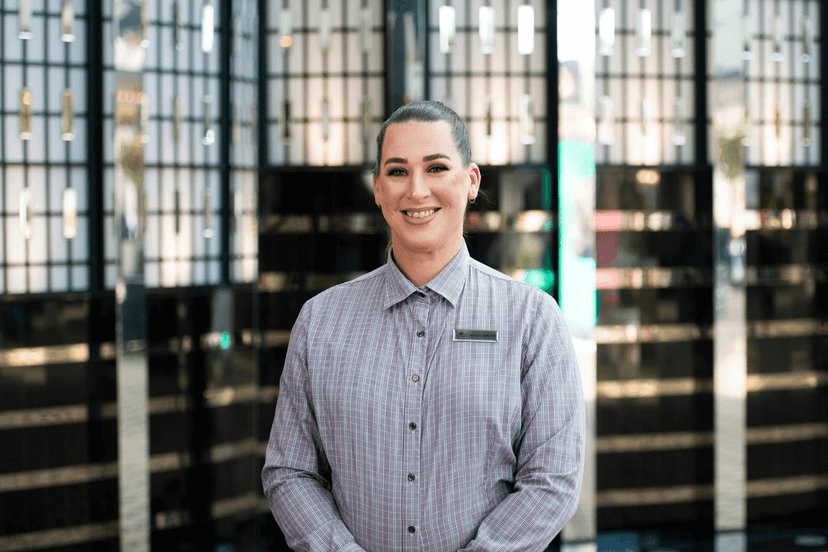 Ashley smiles in uniform and a name tag in the hotel foyet