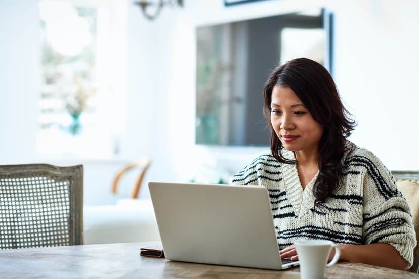 A woman sits at a table with a laptop