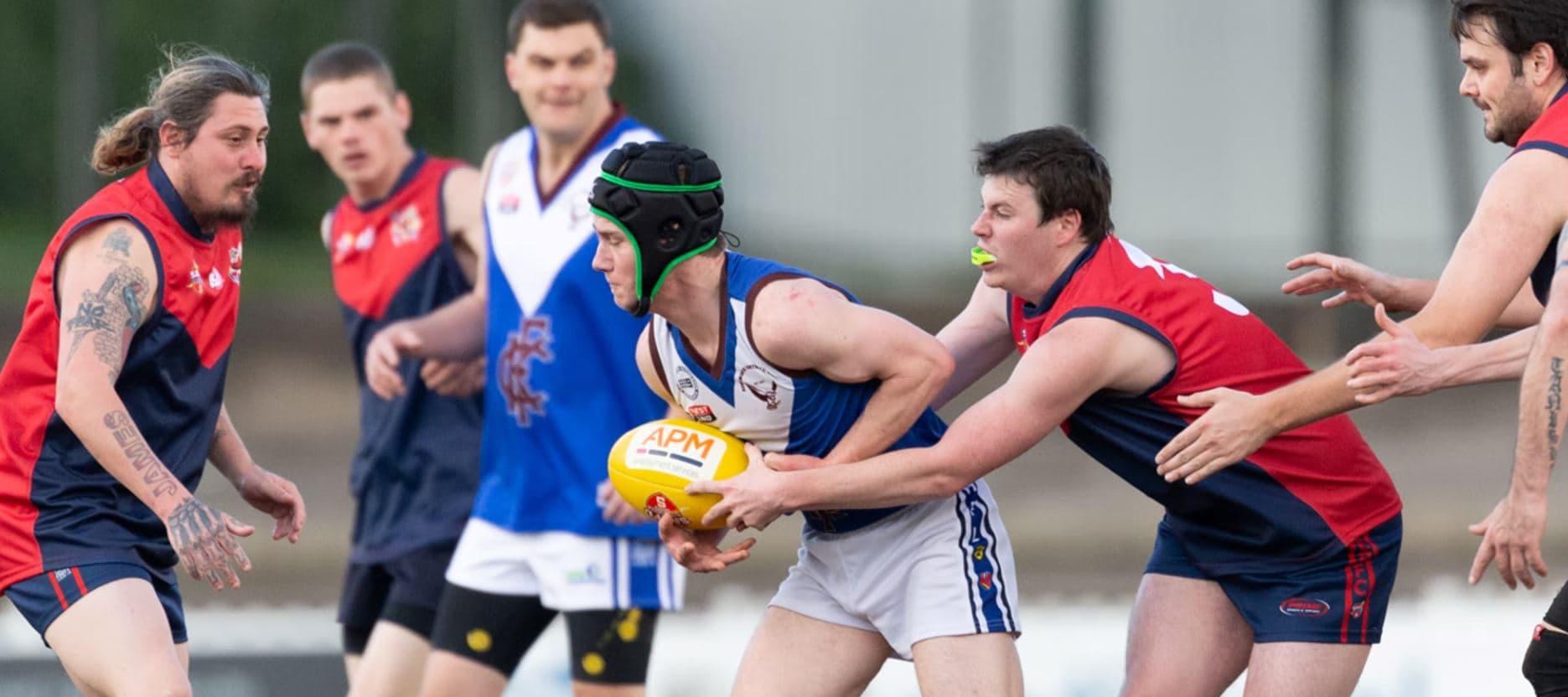 footy players passing a ball with the APM logo
