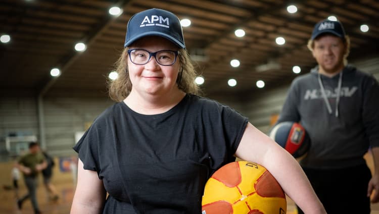 A young girl with a basketball and an APM cap