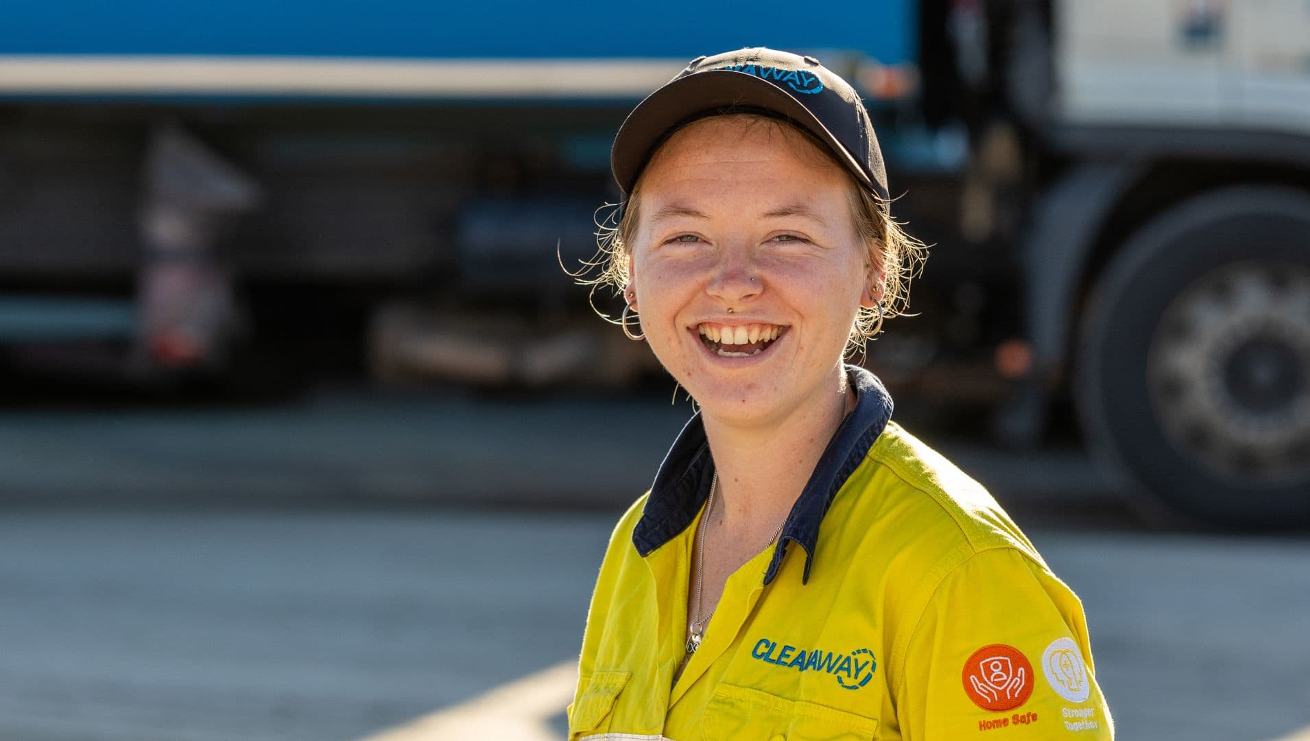 Nariah a young woman smiles at the camera in her high vis work clothes and black cap