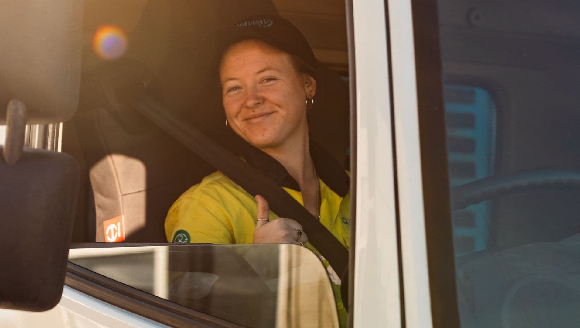 Nariah a young woman smiles at the camera in her high vis work clothes and black cap