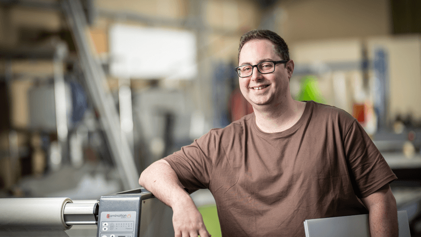 Inclusive employment participant Sean smiles in his new workplace.